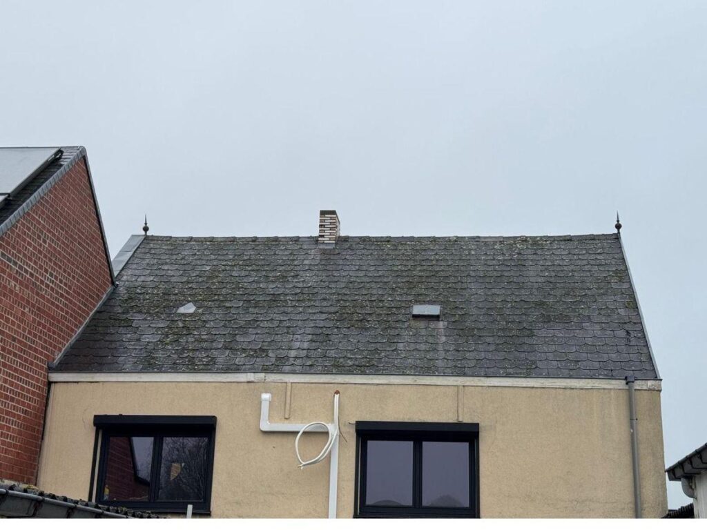 Verouderd hellend dak met mos en verweerde dakbedekking voor de renovatie